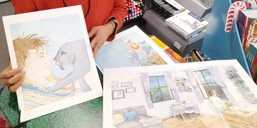 Deux aquarelles originales de l'album Tiê posées sur une table : l'enfant et son chat, et la double page du salon la nuit